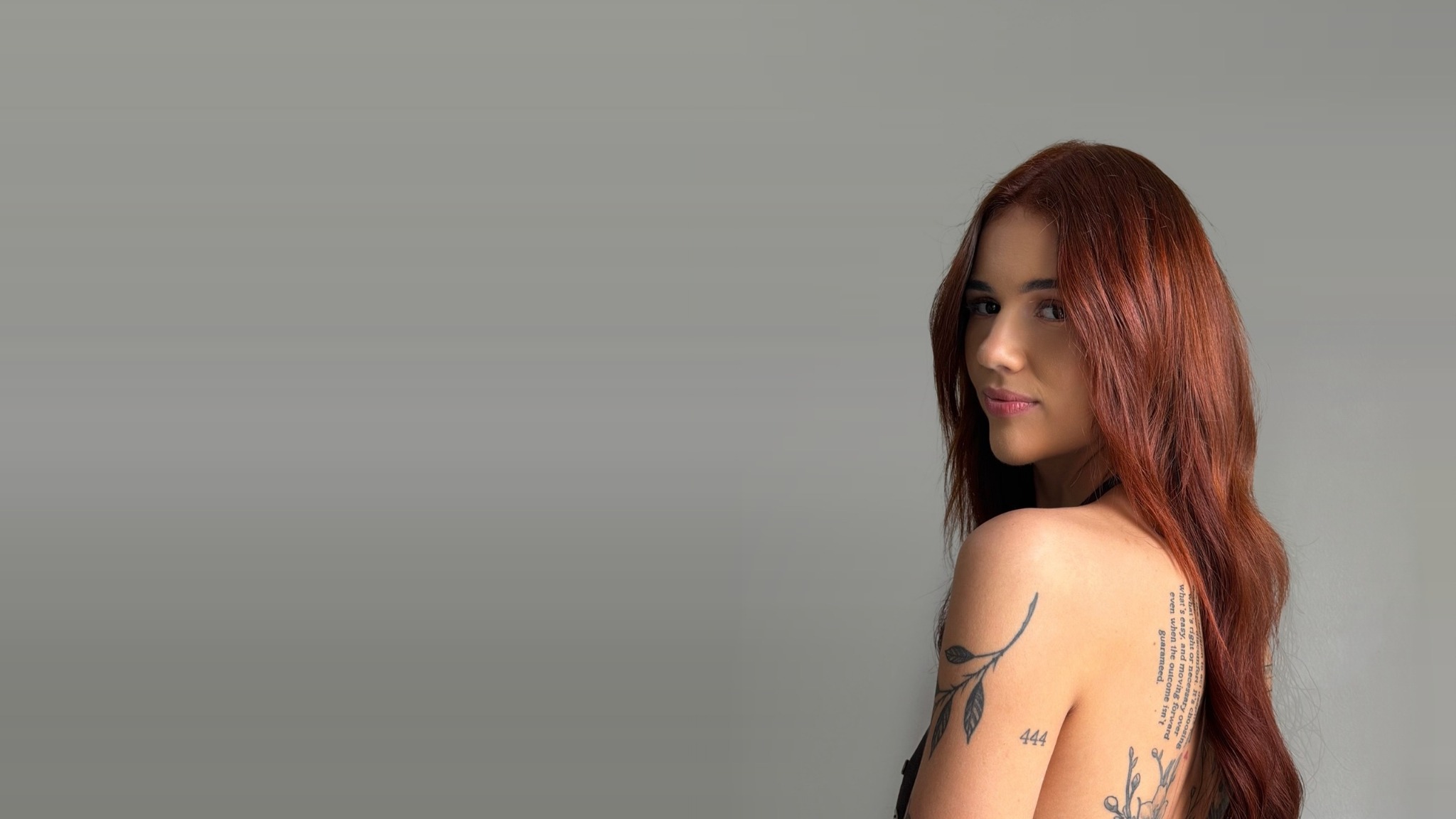 Client with long auburn hair against a plain grey studio backdrop.